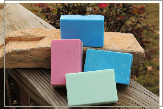 Four bars of soap on a wooden surface.