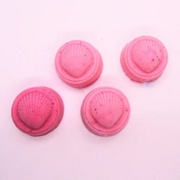 Four pink shell-shaped soaps on white.