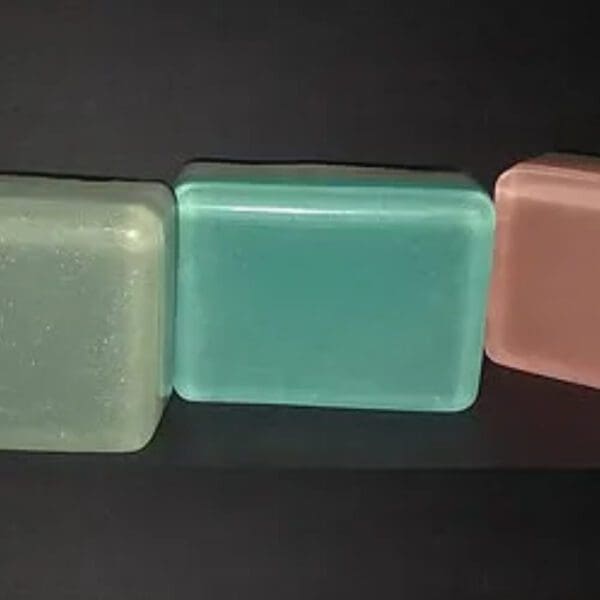 Three rectangular bars of soap in green, white, and pink.