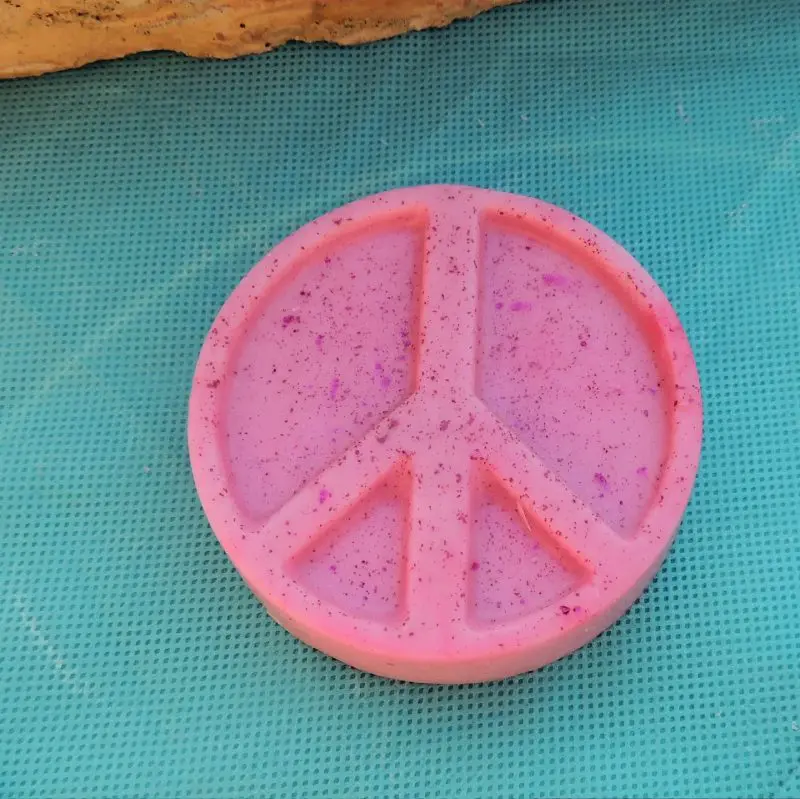 Pink peace sign with glitter on blue mat.