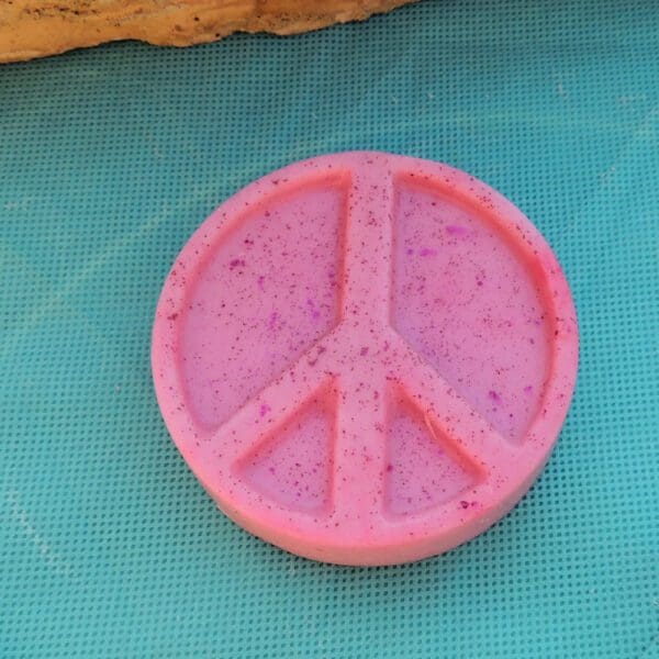 Pink peace sign with glitter on blue background.