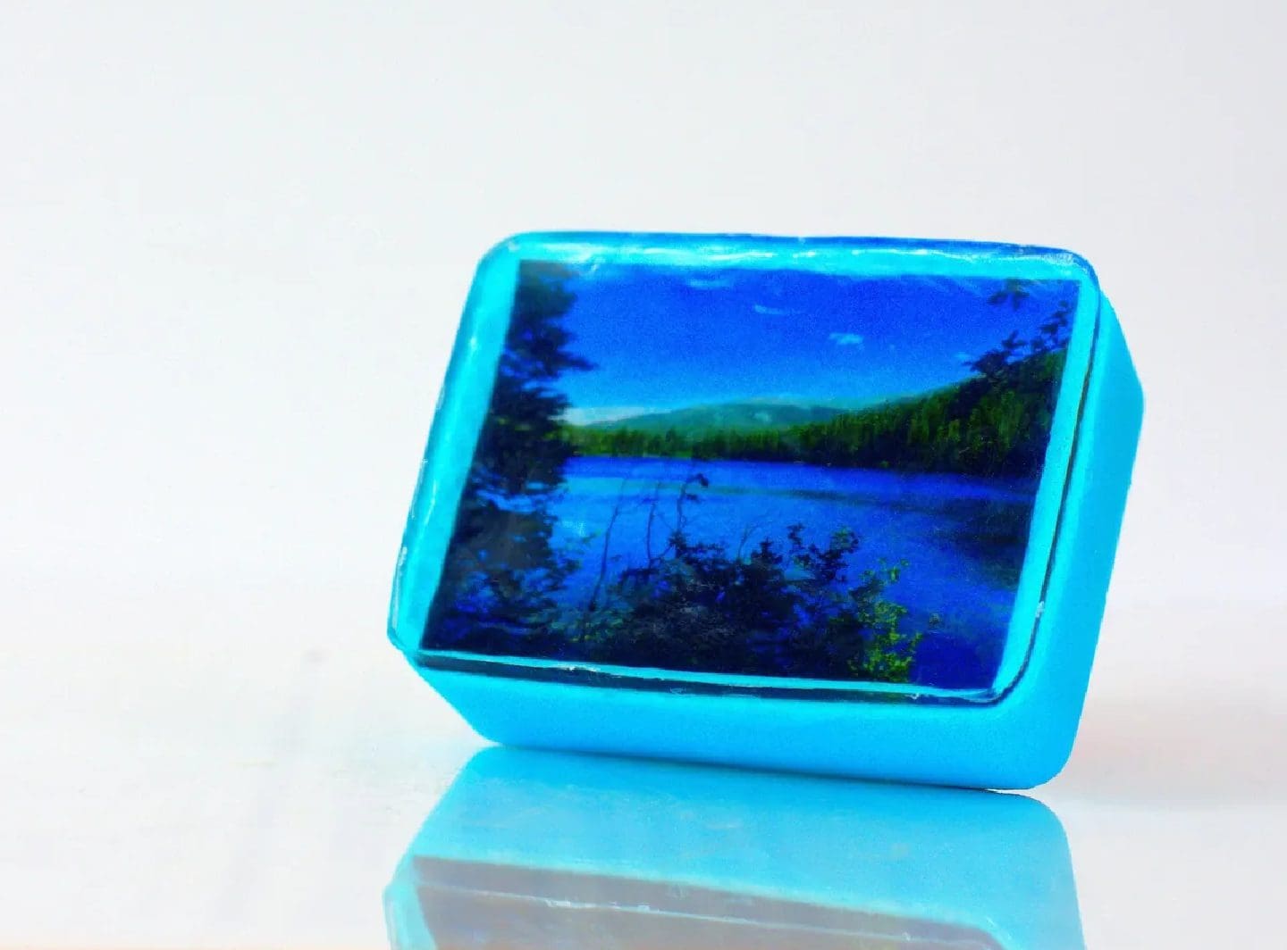 Blue square with lake and trees.