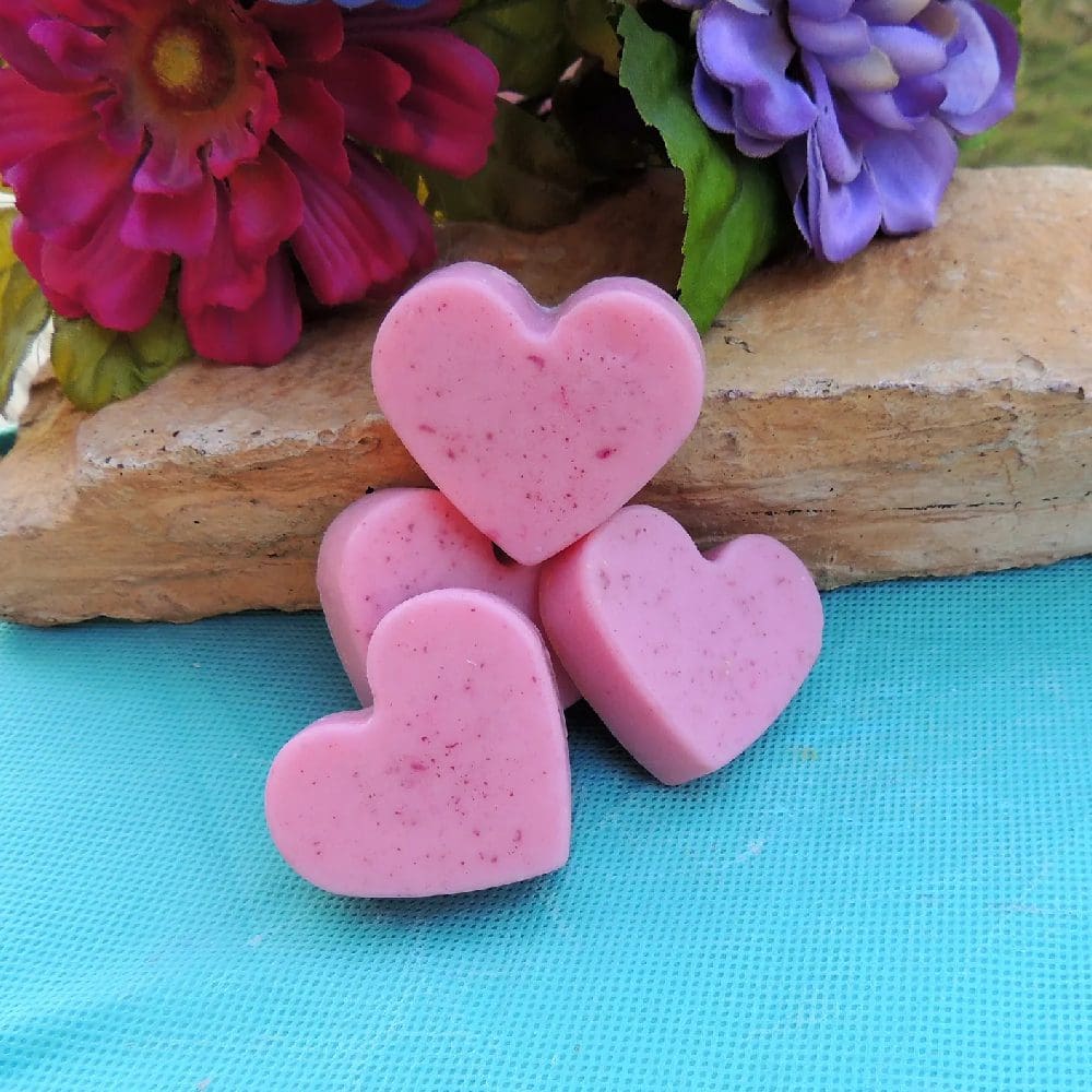 Four pink heart-shaped soaps on blue fabric.