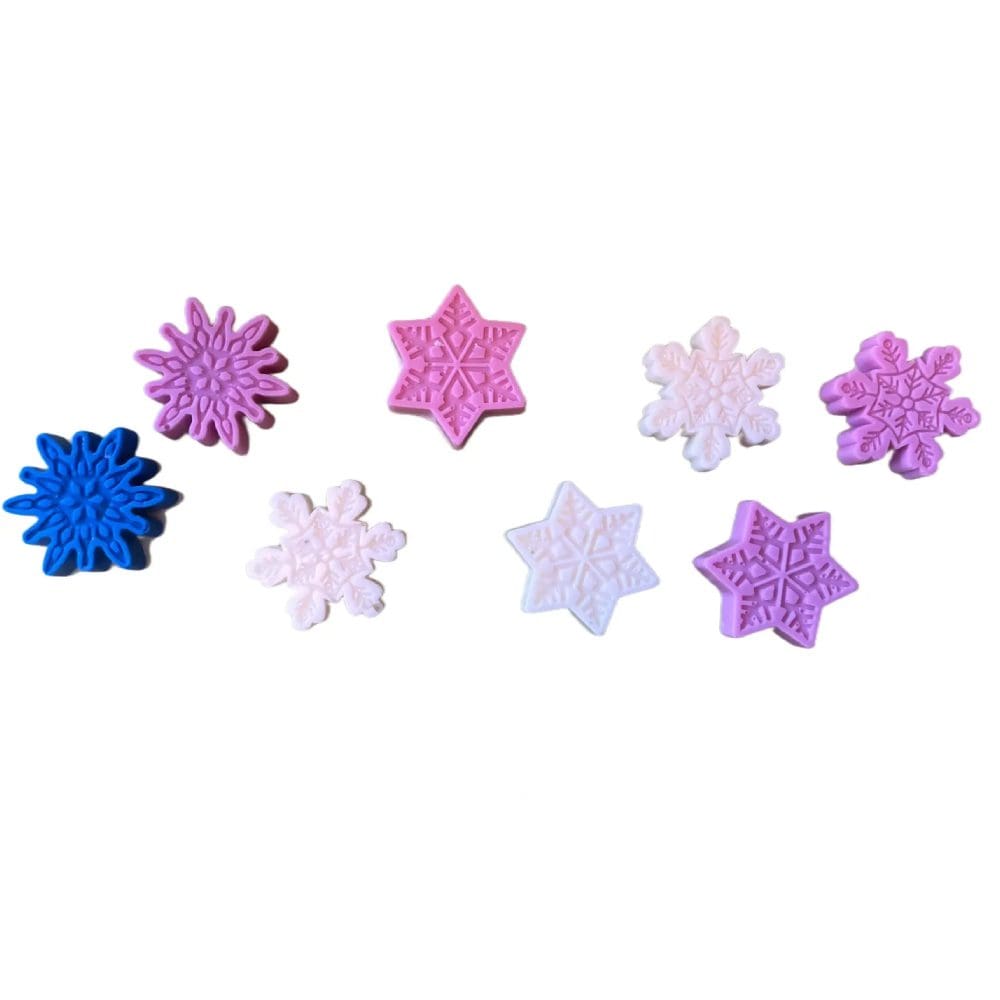 Colorful snowflake shaped soaps on white background.